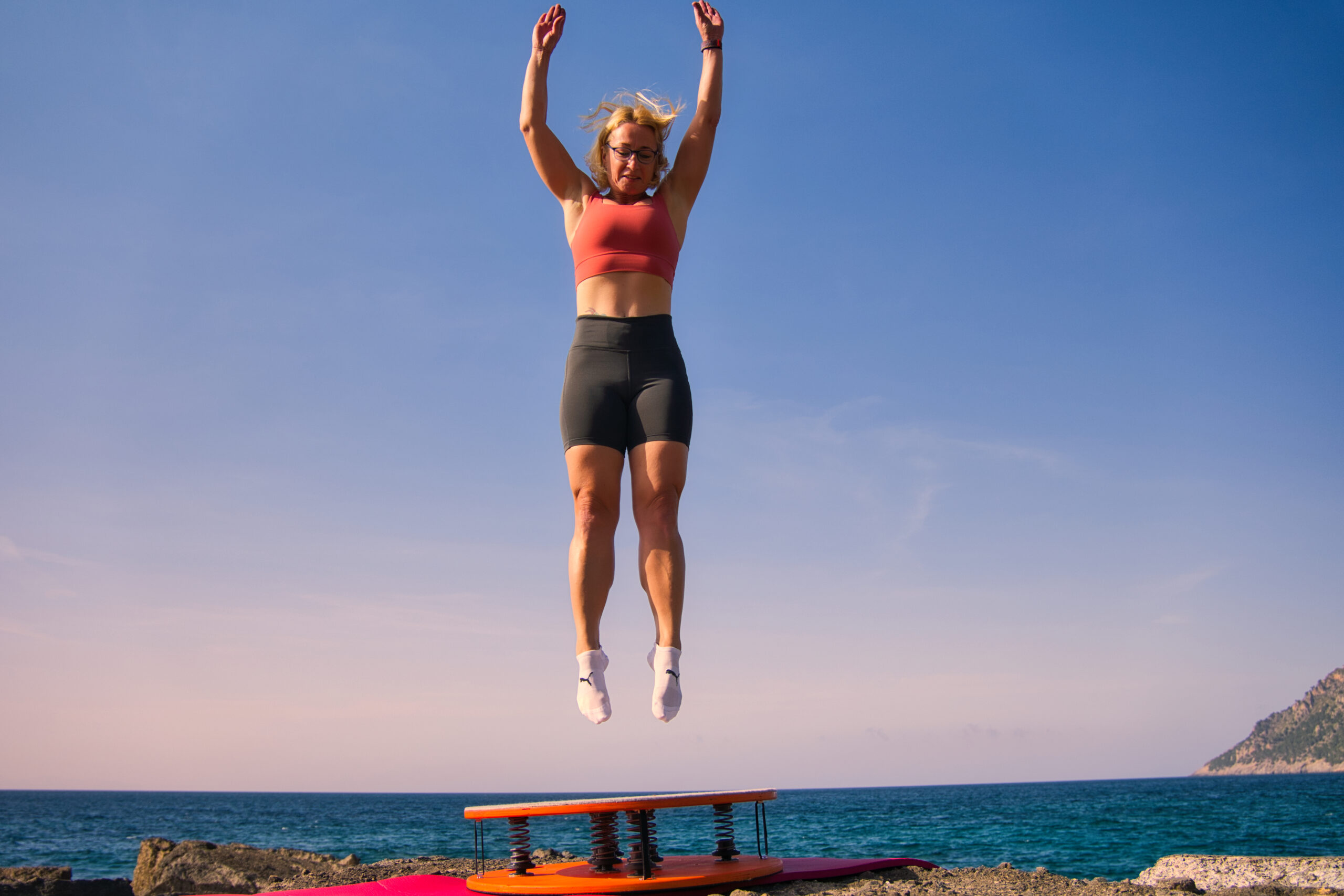 Iris springt vor dem Meer auf Mallorca über dem Jumpmaster – Outdoor-Training